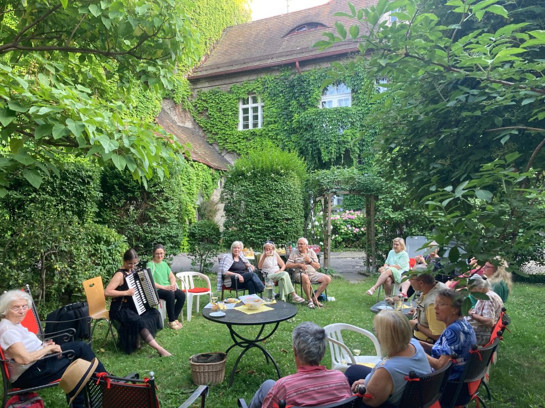 Menschen sitzen im Gartenund singen gemeinsam